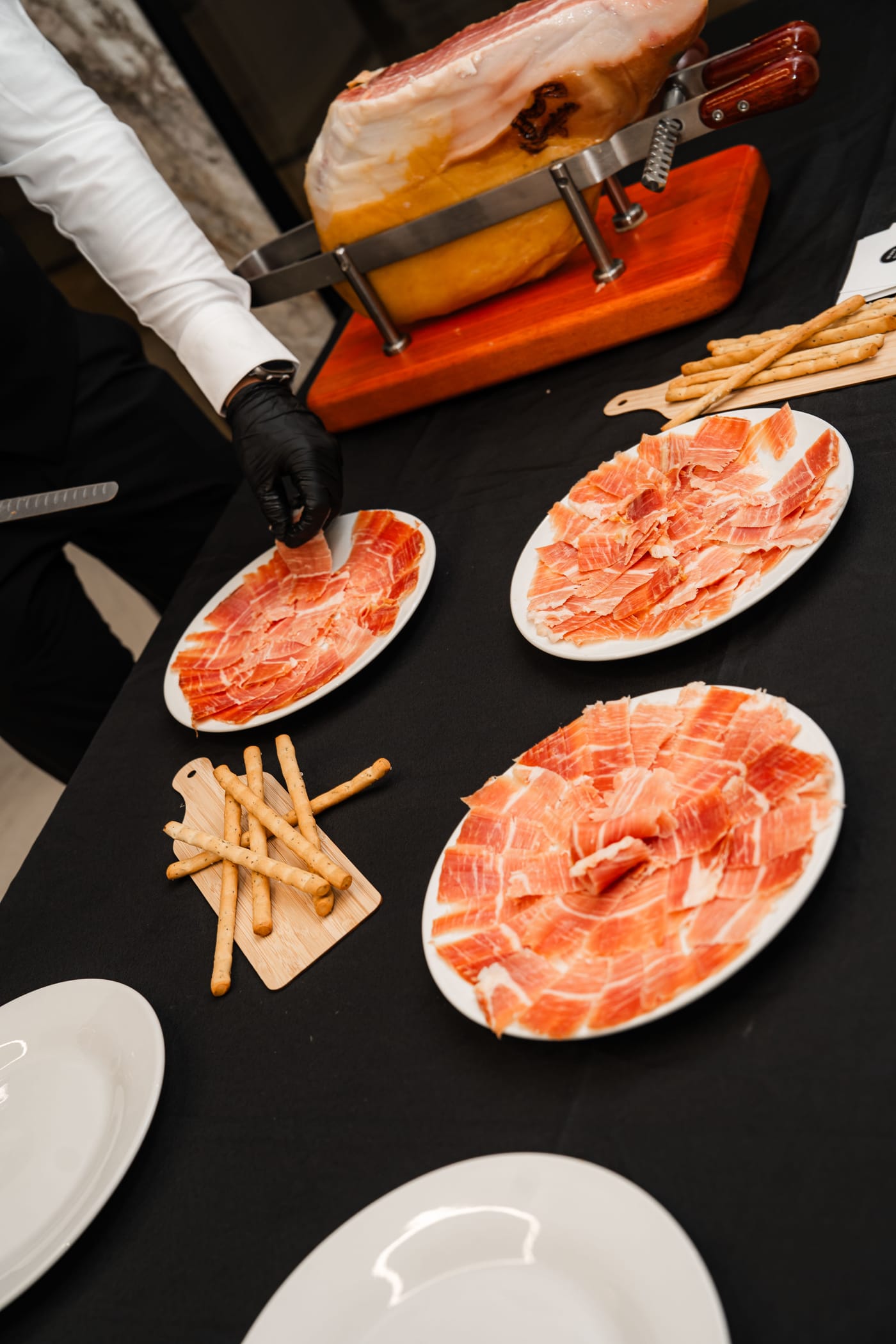 Carving station with plated jamón and breadsticks